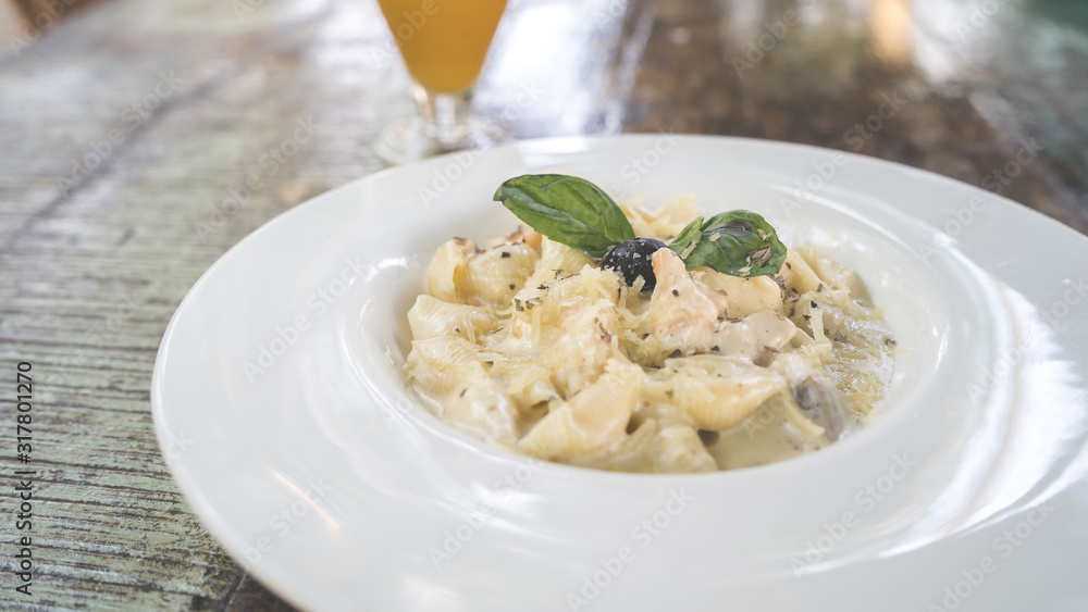 Yummy pasta on cafe table. Closeup plate with portion of tasty pasta with cream sauce placed on table in restaurant