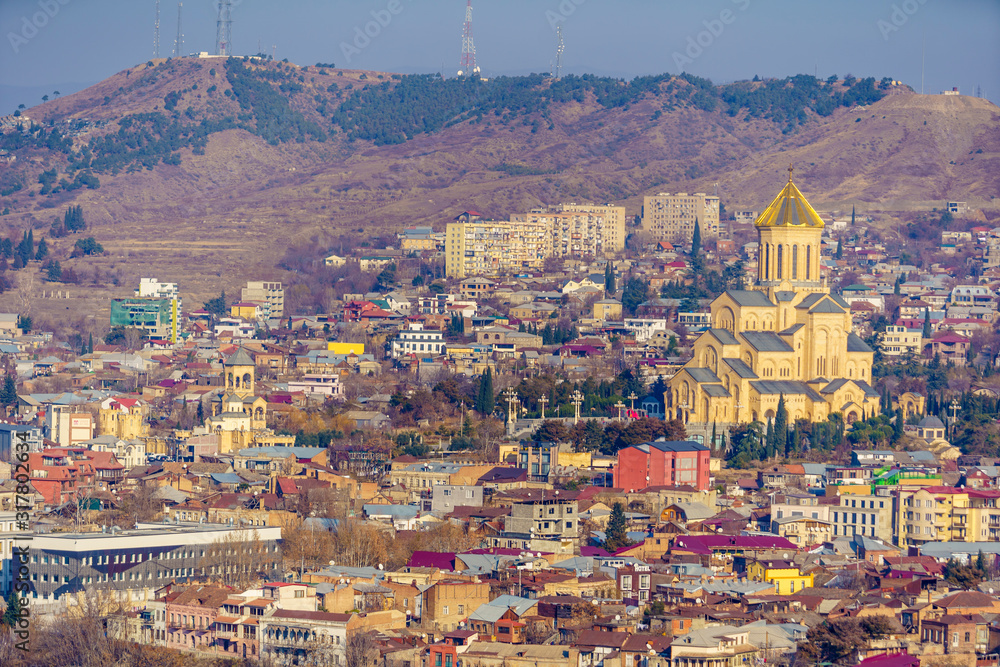Holy Trinity Cathedral in Tbilisi. Panorama from the mountain on the background of the city and surrounding buildings. Filmed at the long focus. Winter.