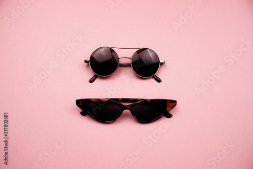 Two pairs of sunglasses flat lay on colorful pink background. Trendy round and cat eye sunglasses. Summer, holidays and vacation concept. Design for web, social media, advertising. Stock photo. © Veronika Kraeva