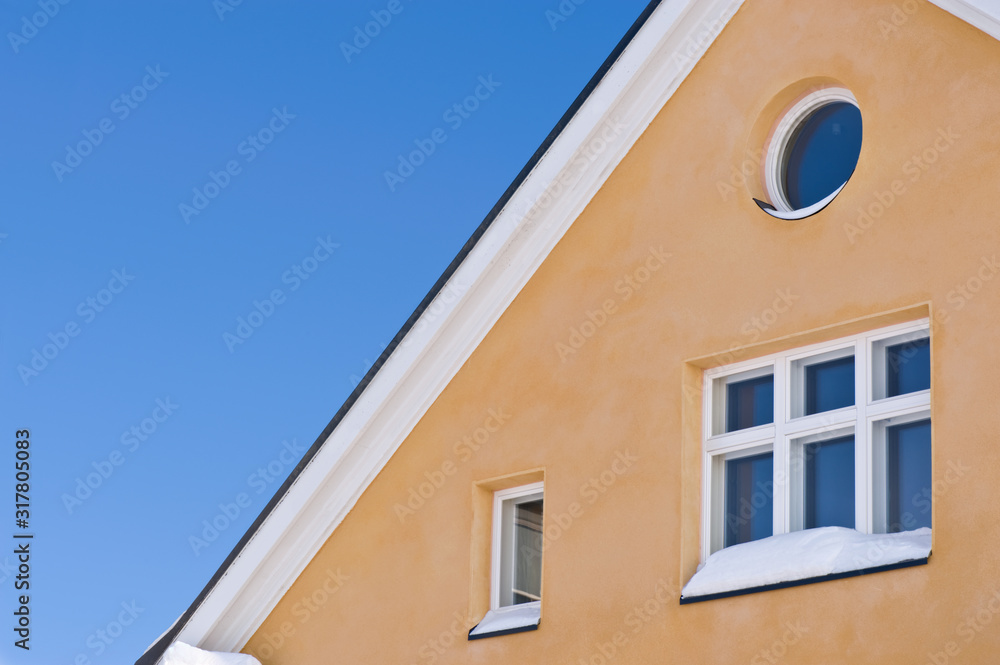 Detail of house exterior against blue sky.