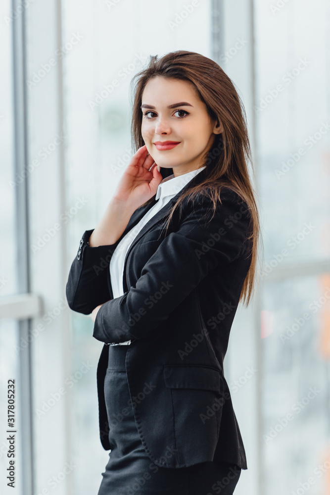Cheerful female stands looking in the window, in her new office expressing pleasant emotions and confidence. Cheerful female stands looking in the window, in her new office expressing pleasant emotions and confidence.