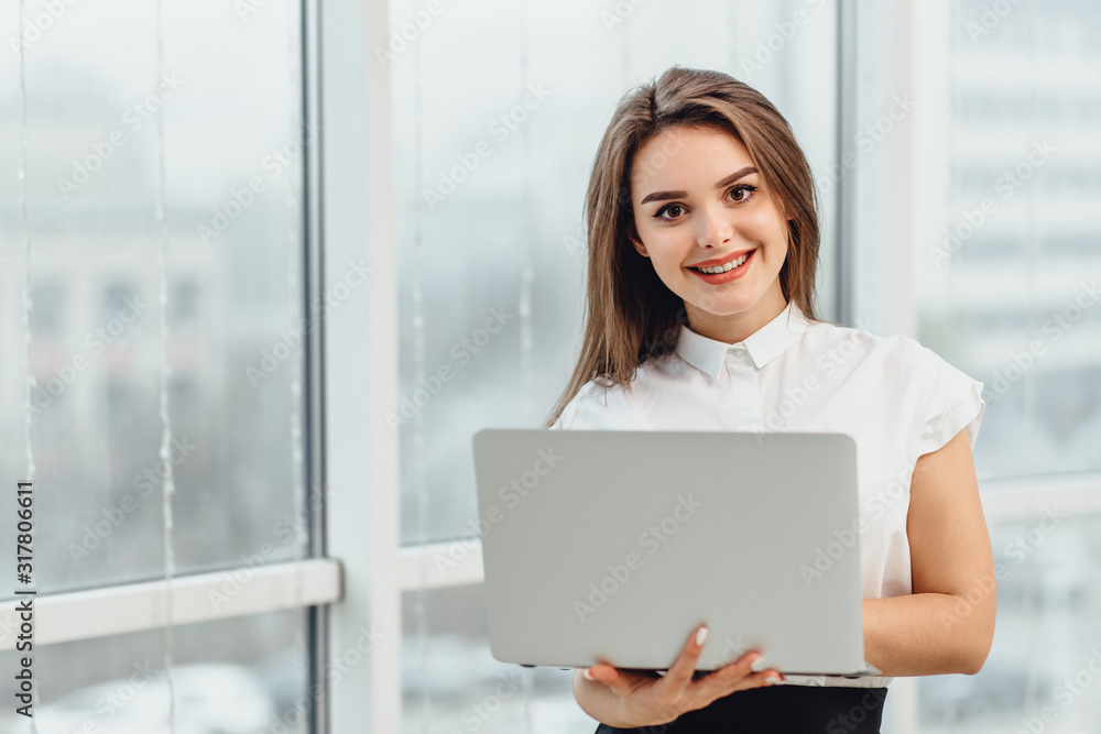 Joyful business woman standin in office, holding laptop. Joyful business woman standin in office, holding laptop.