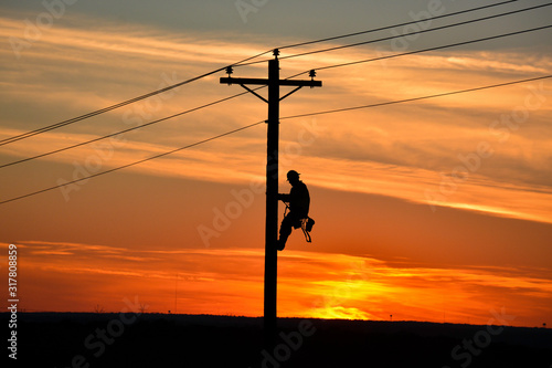 Lineman on pole during sunset