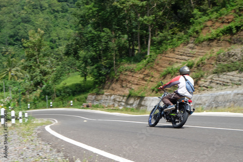 Man riding a classic motorcycle on highway of mountain © YoannesBaskoro