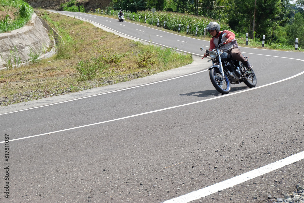 Man riding a classic motorcycle on highway of mountain Man riding a classic motorcycle on highway of mountain