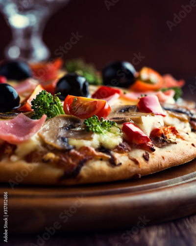 Tasty pizza with ham, broccoli, cherry tomatoes, red pepper and champignon mushrooms. Close up.