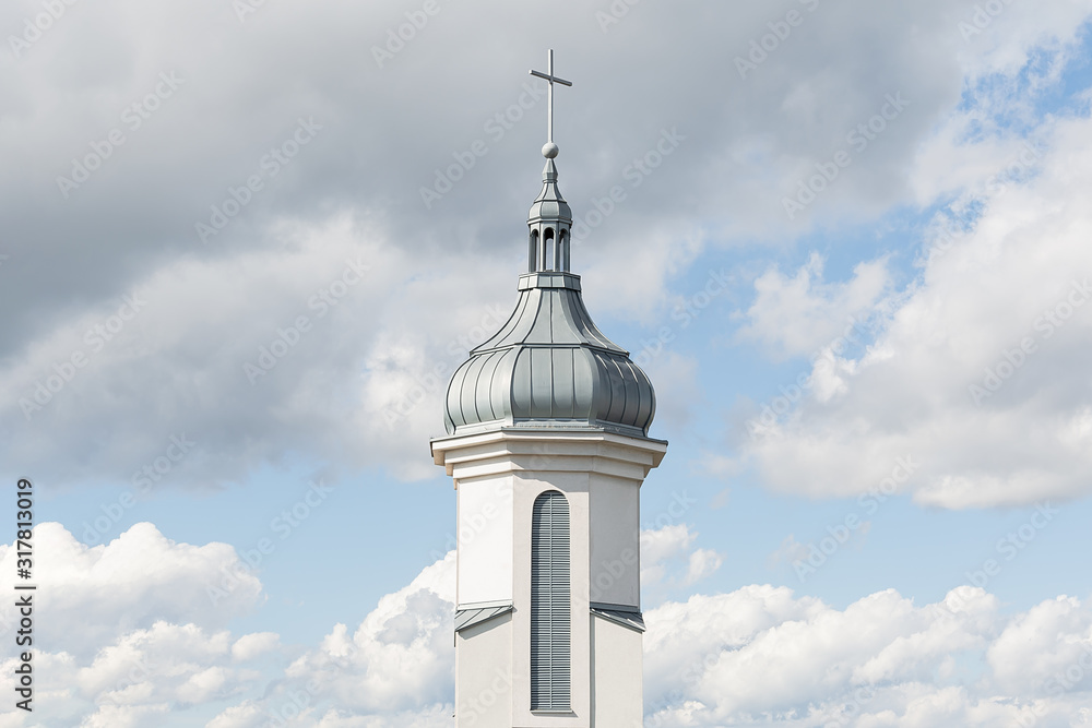 View of the dome and bell tower of a modern Catholic church against a blue sky with clouds. Concept architecture, easter, religion