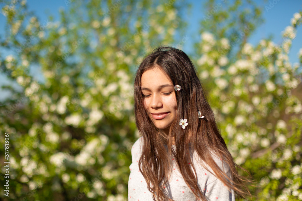 Portrait of a young beautiful teenager girl in a blooming spring green garden Portrait of a young beautiful teenager girl in a blooming spring green garden