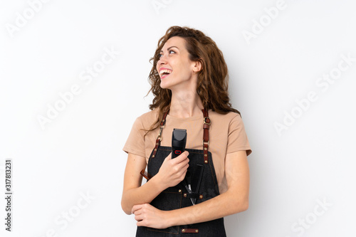 Young pretty woman over isolated background with hairdresser or barber dress and holding hair cutting machine