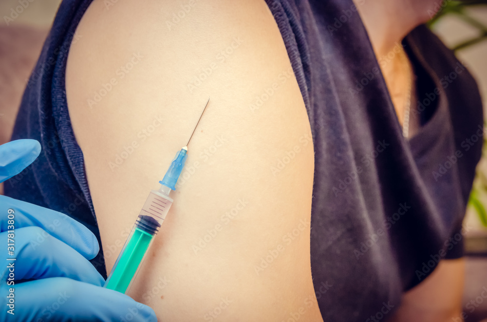 concept of vaccination. Doctor's gloved hand vaccinates a man in a black t-shirt in a close-up concept of vaccination. Doctor's gloved hand vaccinates a man in a black t-shirt in a close-up