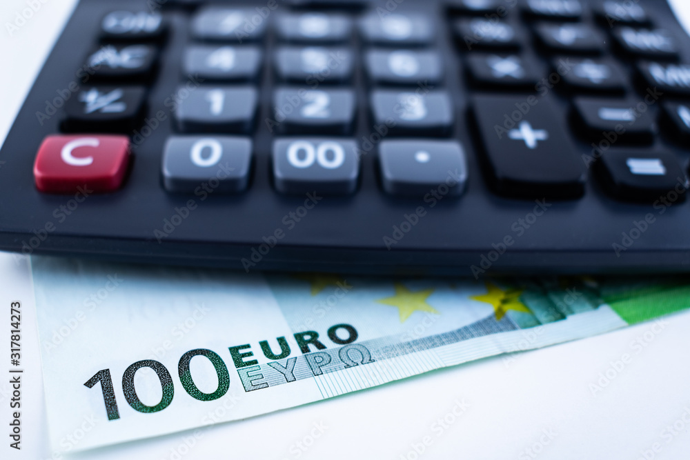 Close-up of a calculator and 100 EURO banknote on a white backround. Finance concept. Close-up of a calculator and 100 EURO banknote on a white backround. Finance concept.