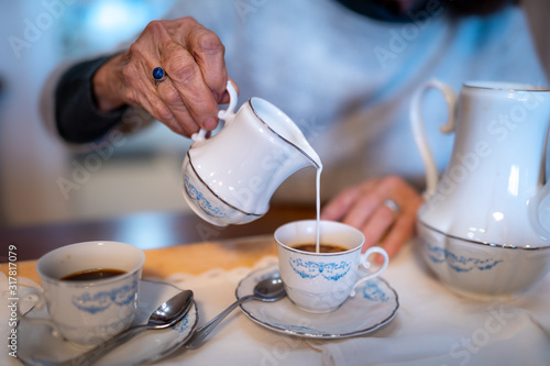 Una mano sirve leche en una taza de café. reunión de personas mayores photo