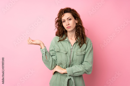 Young pretty woman over isolated pink background unhappy for not understand something © luismolinero