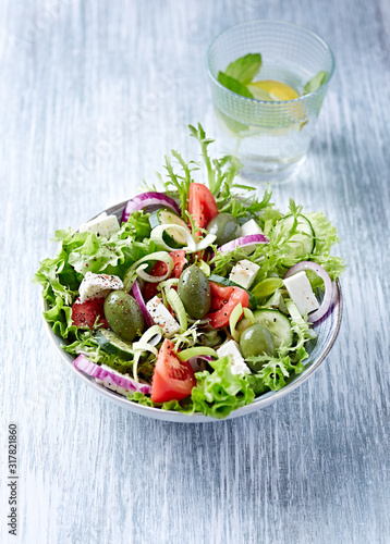 Salad with Green Olives, Tomatoes, Endive, Cucumber and Feta Cheese. Wooden background.
