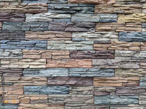 Multi-colored masonry: the wall of the house is made of decorative stone. Beautiful background for design and banners