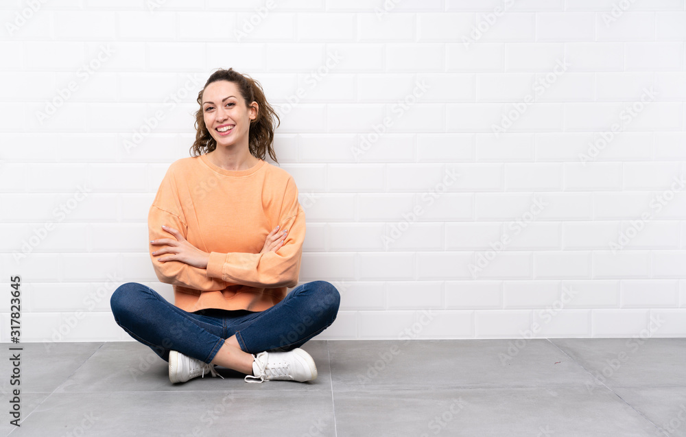 Young woman with curly hair sitting on the floor laughing