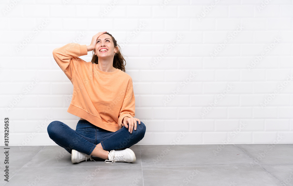 Young woman with curly hair sitting on the floor laughing Young woman with curly hair sitting on the floor laughing