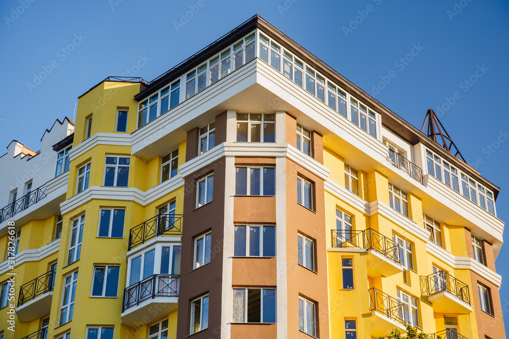 Construction of new multi-story building. Modern residential construction among nature. Residential fund. The city displaces nature. New yellow building and green crown of trees