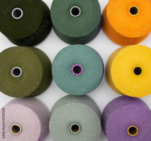 Multi-colored bobbins of yarn on a white background. Top view on colored spools of thread.Textile reels on white background.