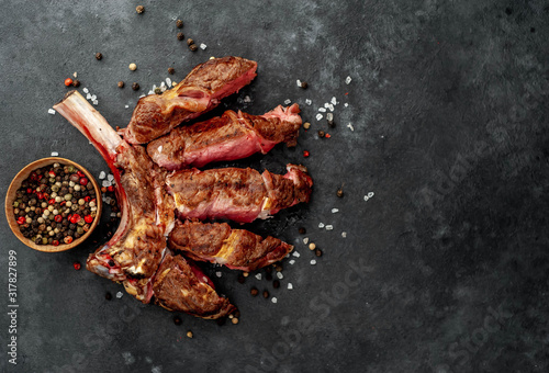steak - sliced ​​grilled beef tomahawk with spices on a stone background. with copy space for your text