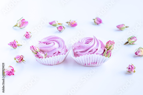 Pink fruit marshmallows and dried buds of roses on the white background. 