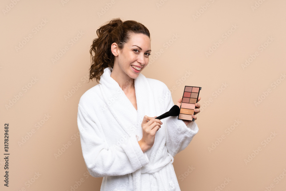Young woman in a bathrobe with makeup palette over isolated background