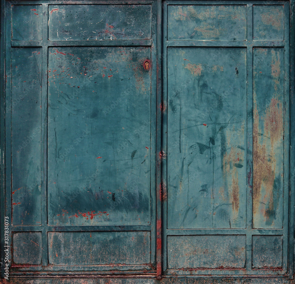 Dirty and rusty blue or green metallic gate of an abandoned factory - double iron door texture with a grunge steampunk aesthetic background