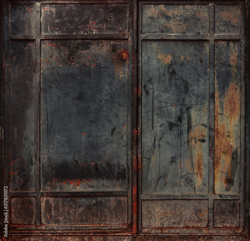 Dirty and rusty black metallic doors of an abandoned factory looking like the gates of the Hell- double iron surface texture with a grunge steampunk aesthetic background