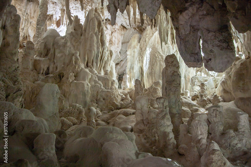 White cave with massive stalactites and stalagmites with lit background. Yarrangobilly Caves, Kosciuszko National Park, NSW, Australia.