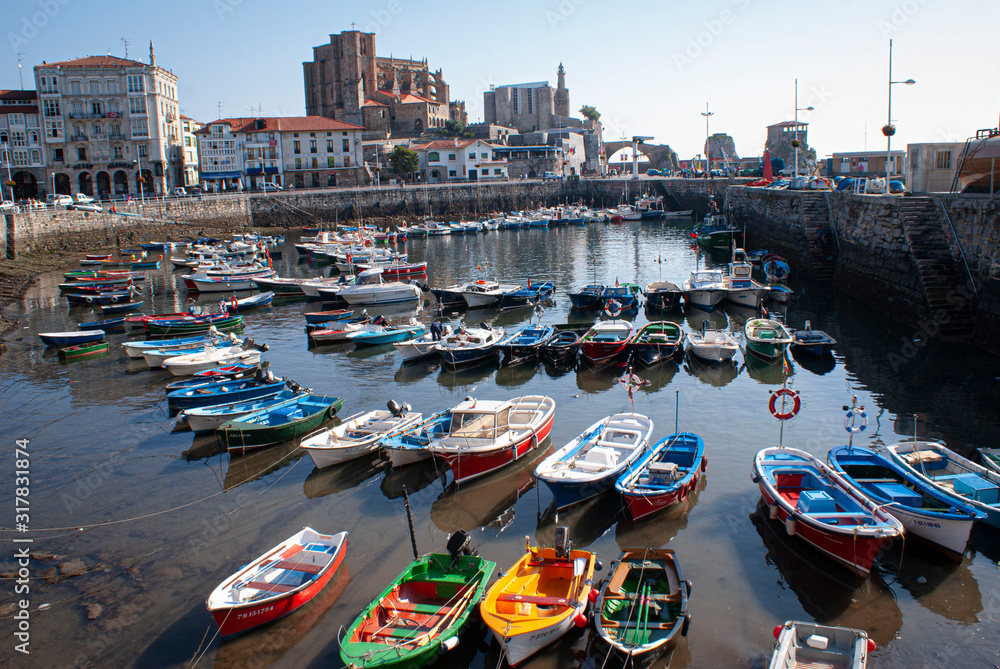 Port in Castro Urdiales, Cantabria; Spain. Image of colored boats and in the background the Church is Santa Maria de la Asunción. Image.