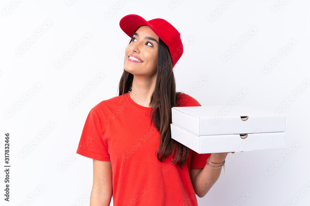 Pizza delivery woman holding a pizza over isolated white wall looking up while smiling Pizza delivery woman holding a pizza over isolated white wall looking up while smiling