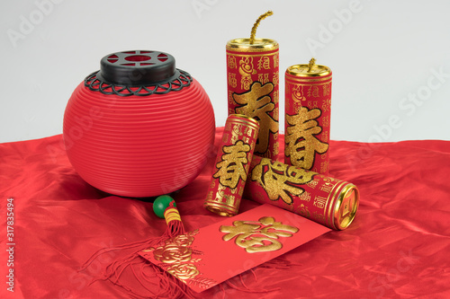 Traditional Chinese golden firecrackers, angpow with Chinese character FU refer to fortune good luck, wealth, money flow on red cloth with red tanglong lantern.