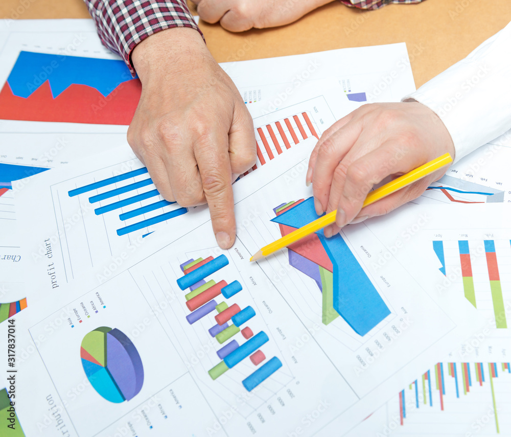 Business people discussing the charts and graphs showing the results of their successful teamwork Business people discussing the charts and graphs showing the results of their successful teamwork