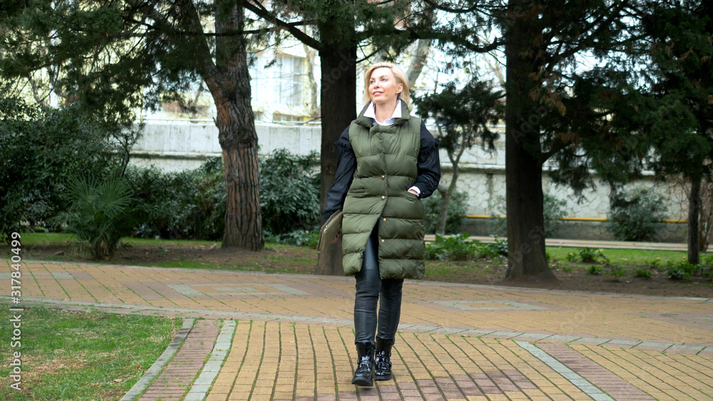 beautiful stylish trendy blond woman walking in a city Park in autumn