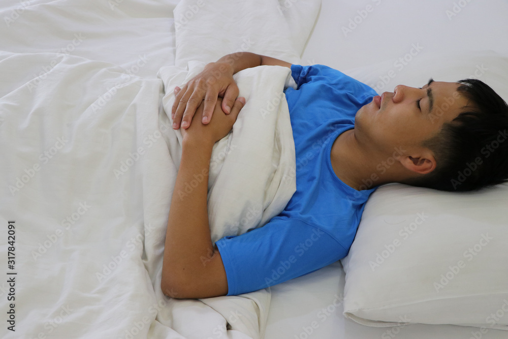 A cute Asian young man is sleeping on a bed. A cute Asian young man is sleeping on a bed.