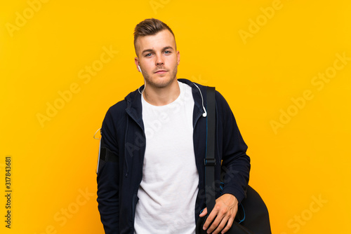 Young blonde sport man over isolated yellow background © luismolinero