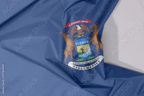 Michigan fabric flag crepe and crease with white space. State coat of arms on a dark blue field.
