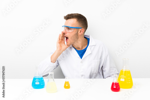 Young scientific with lots of laboratory flask shouting with mouth wide open