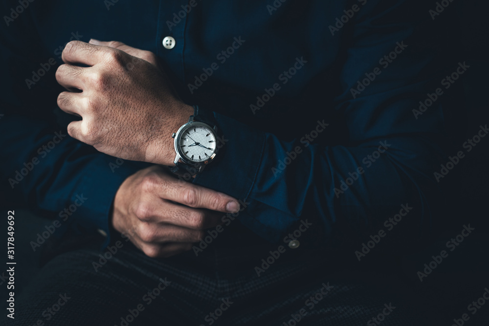looking at luxury watch on hand check the time.man posing on black background.concept for managing time organization working,punctuality,appointment.fashionable wearing stylish