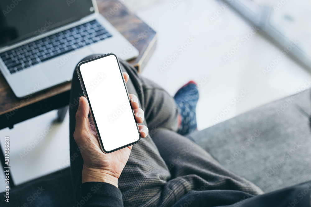 Mockup image blank white screen cell phone.man hand holding texting using mobile on sofa at home office.background empty space for advertise text.people contact marketing business,technology