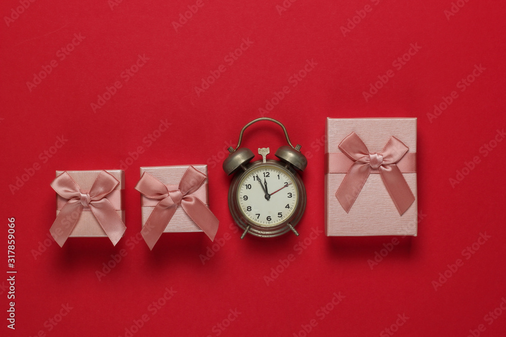 Retro alarm clock and gift boxes with bow on red background. 11:55 am. New Year, Christmas.concept. Top view Retro alarm clock and gift boxes with bow on red background. 11:55 am. New Year, Christmas.concept. Top view