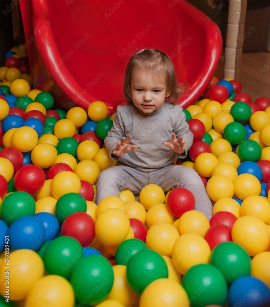 Little Joyful girl in the pool with colorful balls. Children's entertainment center Little Joyful girl in the pool with colorful balls. Children's entertainment center