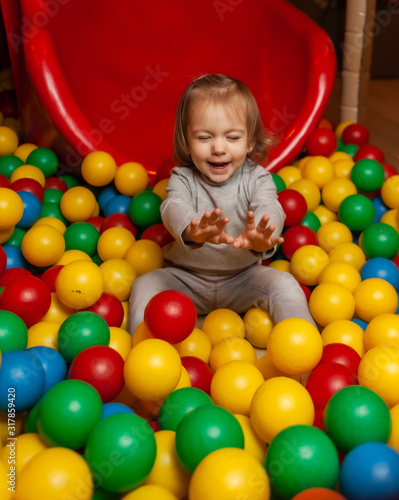 Little Joyful girl in the pool with colorful balls. Children's entertainment center