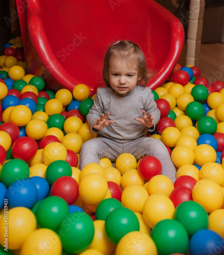 Little Joyful girl in the pool with colorful balls. Children's entertainment center