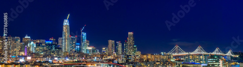 San Francisco skyline night panorama with city lights, the Bay Bridge and trail lights