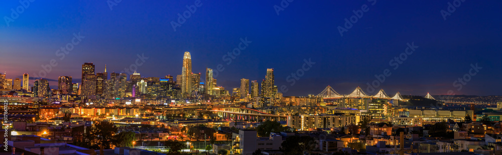 San Francisco skyline night panorama with city lights, the Bay Bridge and trail lights