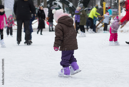 Side view of caucasian child of three years old skating on the rink in wintertime