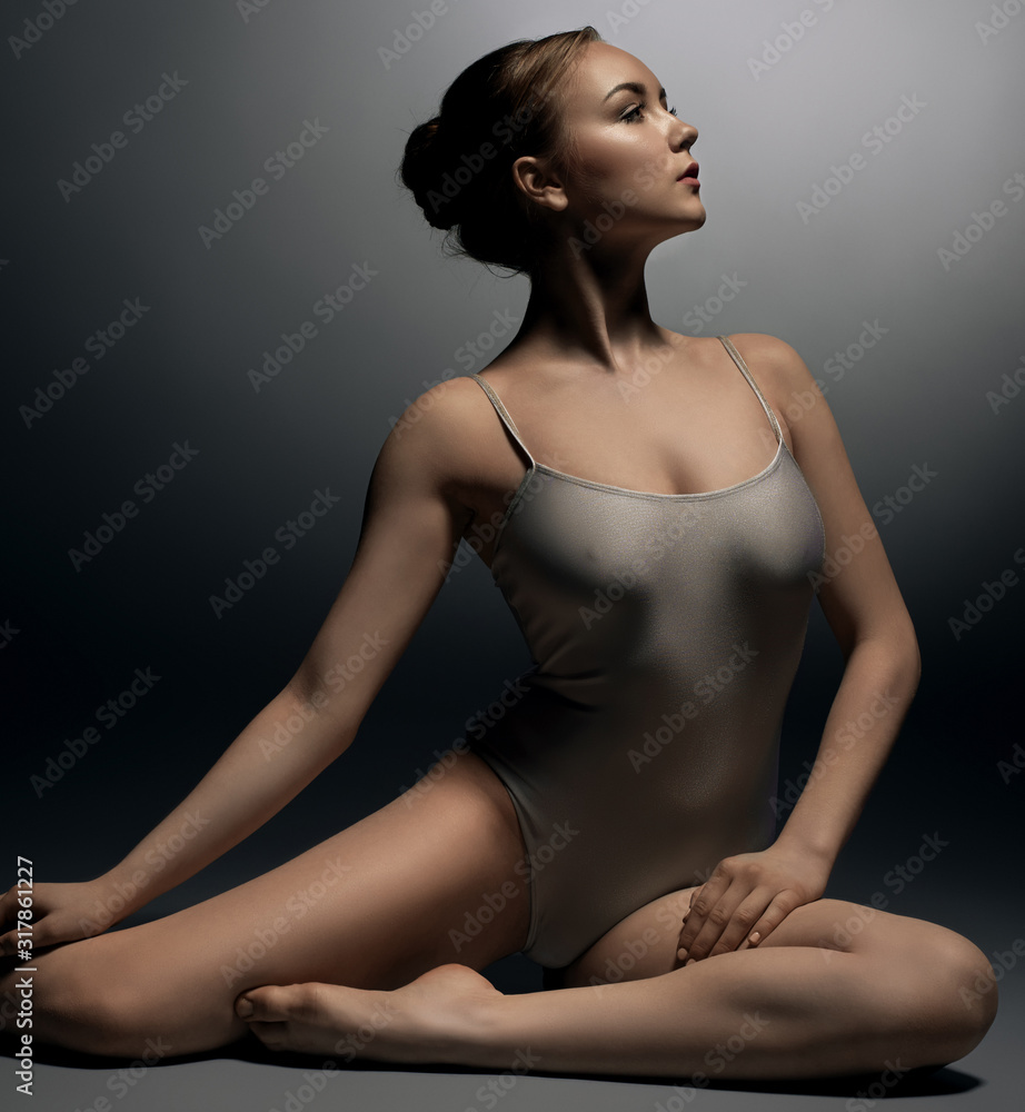 Fototapeta premium Sexy gymnast in ecru bodysuit in split in profile
