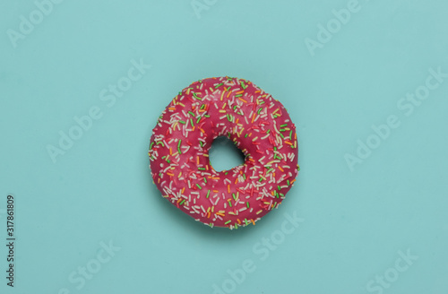 Minimalistic food still life. Glazed donut on blue pastel background. Vanilla color trend. Top view