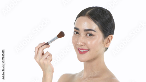 Beauty concept. A beautiful woman is using a brush to brush her face. 4k Resolution.